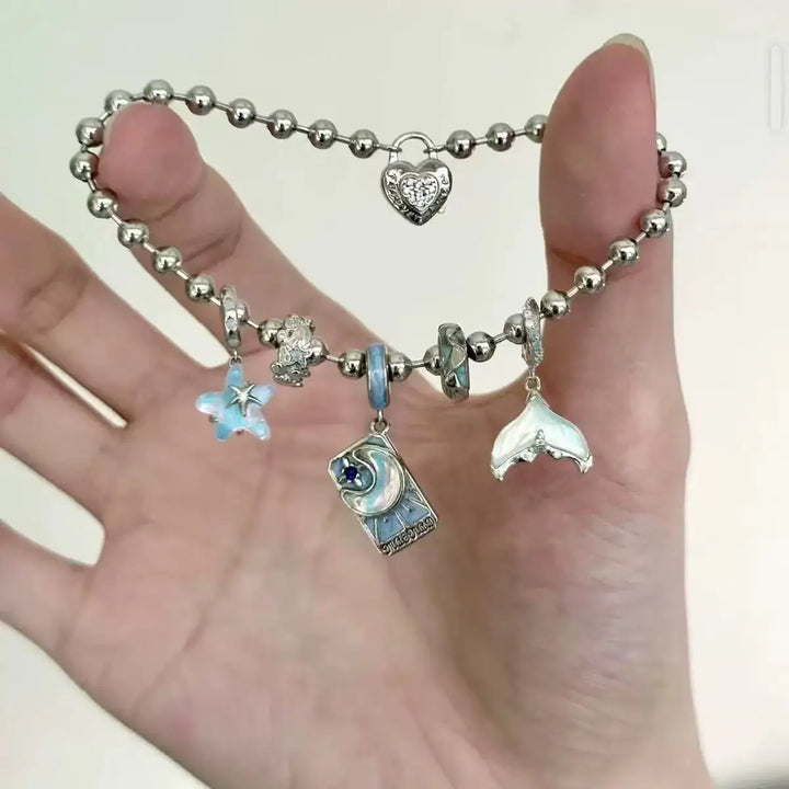 Bracelet with various charms held in a hand against a neutral background