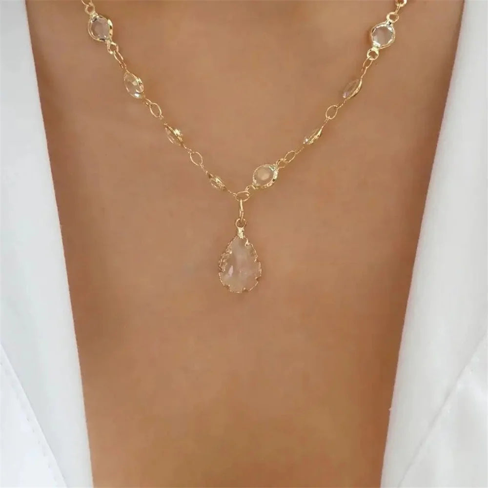Gold-tone necklace with fine chain links and pale crystal teardrop pendant at center.