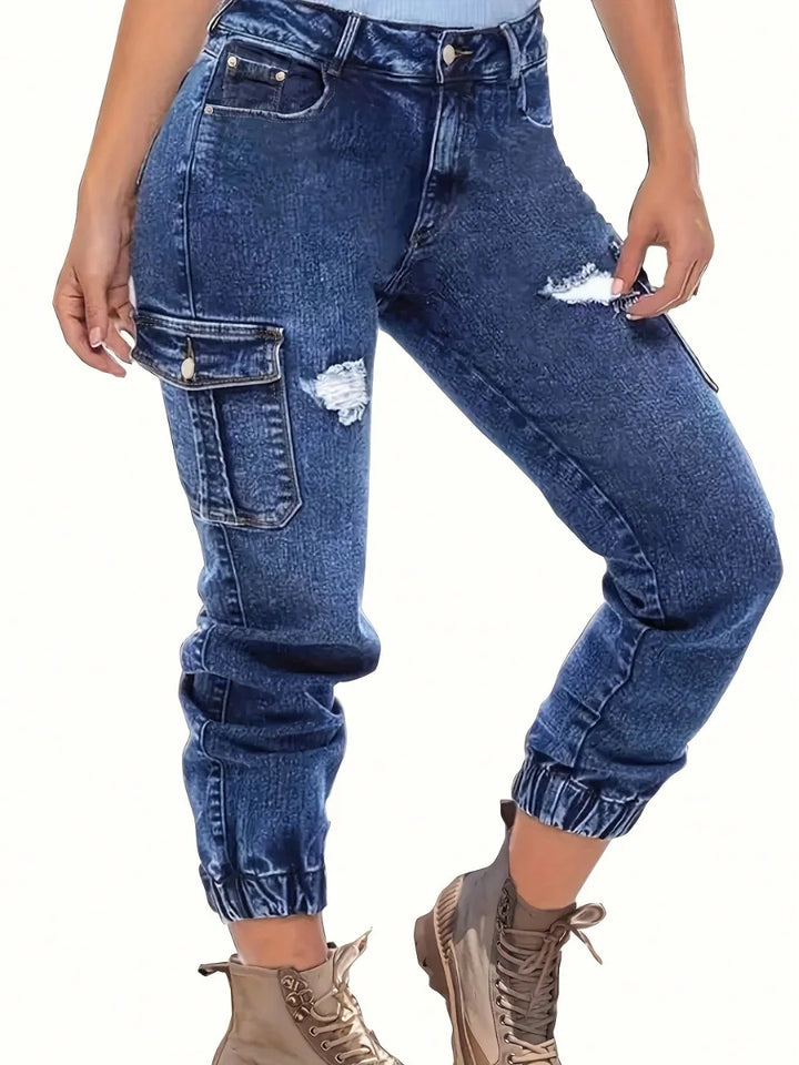 High-waist dark blue denim jeans with side cargo pockets and ripped knee detail.