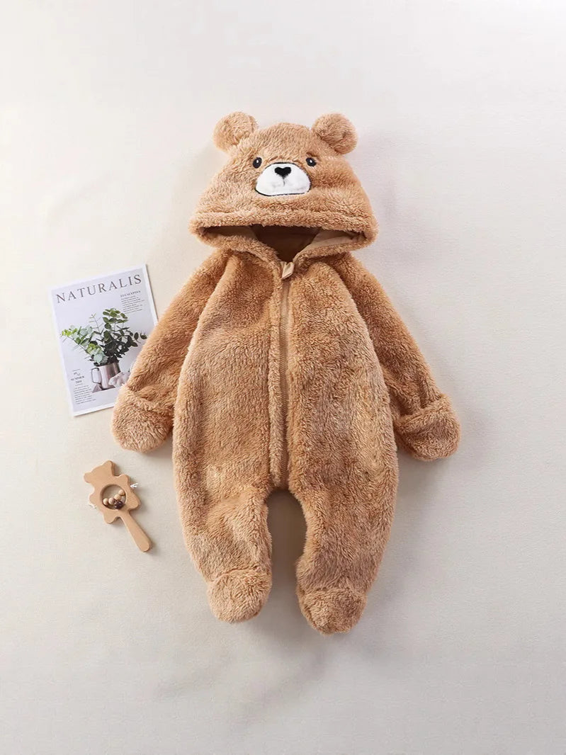 Brown teddy bear onesie on a light gray background with a magazine and wooden toy.