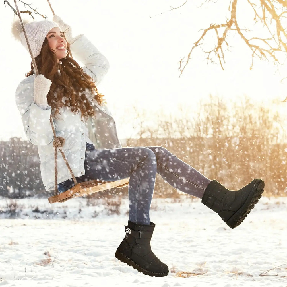 Woman in winter clothing with black boots sitting on a swing in a snowy landscape.