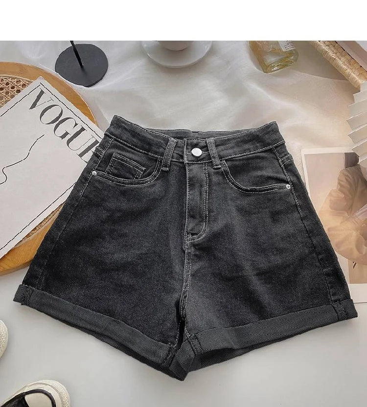 Black denim shorts on a light surface with a magazine and other items in the background