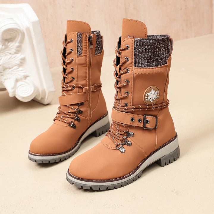 Women’s tan lace-up winter boots with buckle strap, snowflake badge, and rugged sole.