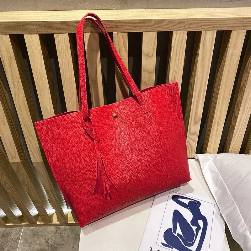 Red tote bag on a wooden surface with a white paper featuring a logo.