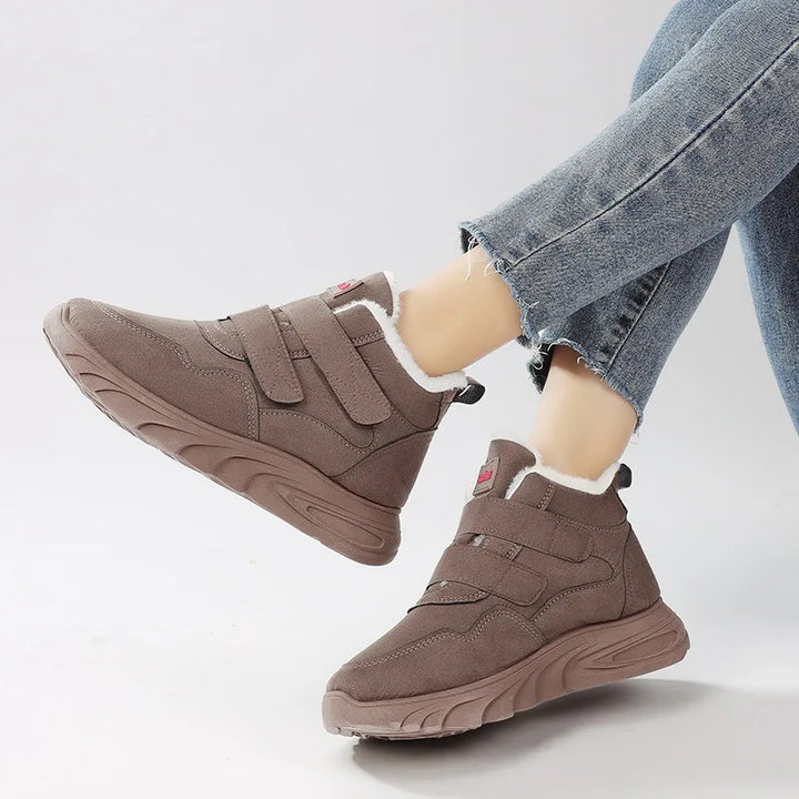 Brown winter boots with white lining worn with light blue jeans on a white background