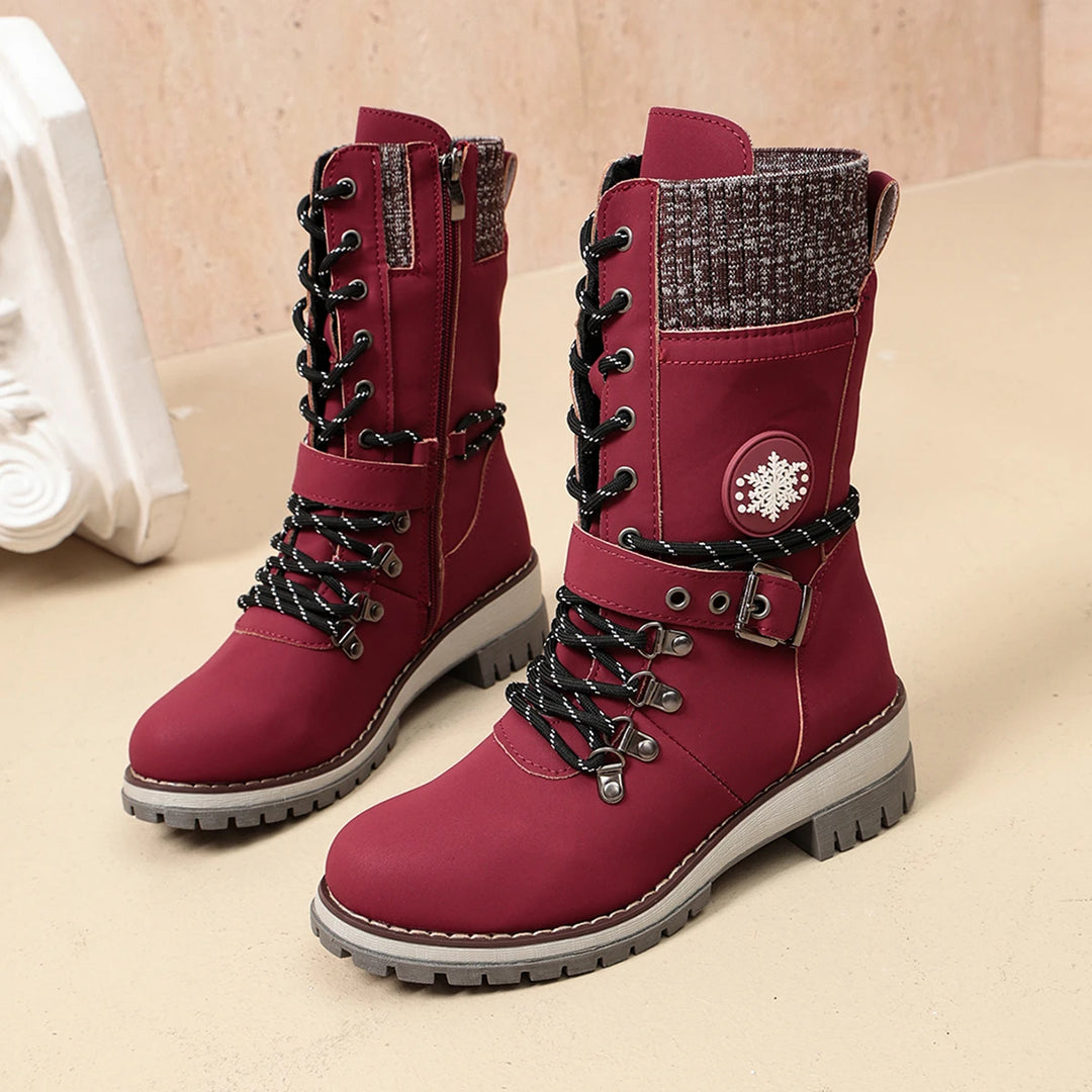 Women’s burgundy lace-up winter boots with buckle strap, snowflake badge, and tread sole.