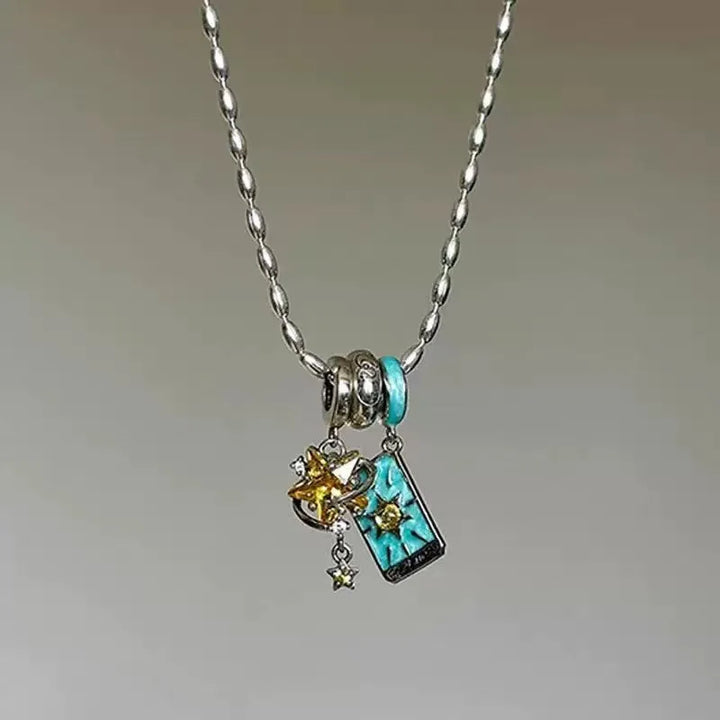 Silver charm bracelet held over a blue jewelry box with star patterns.