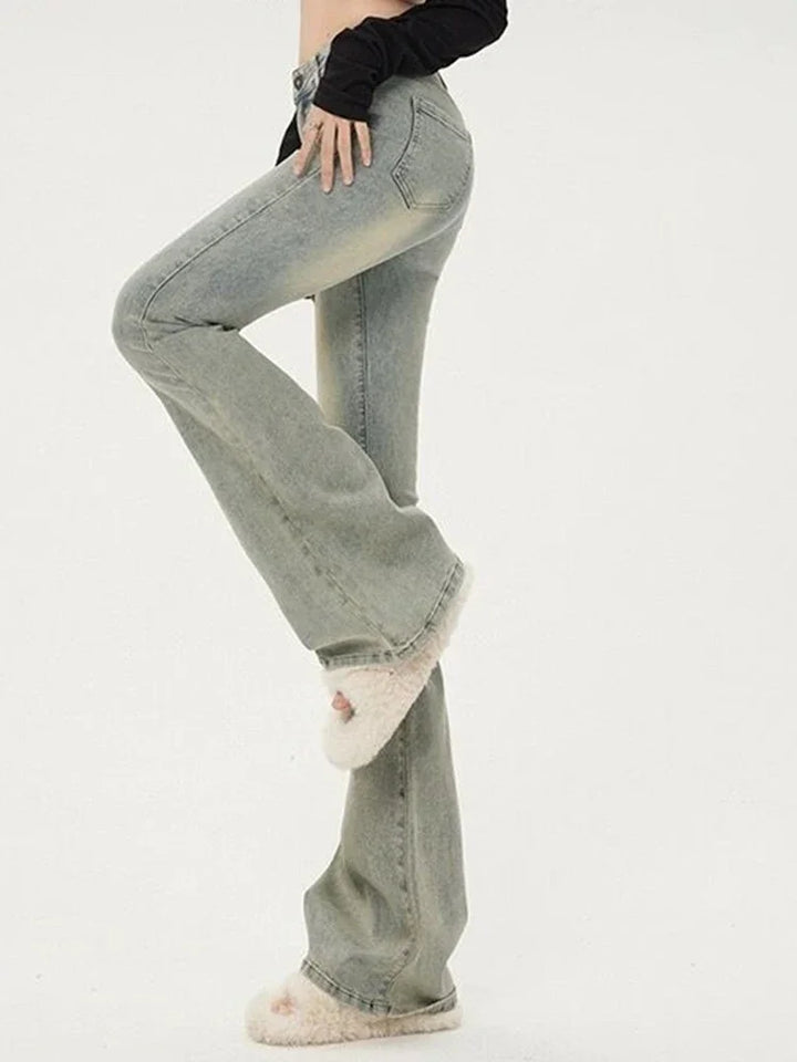 Person wearing light blue jeans and white shoes on a plain background