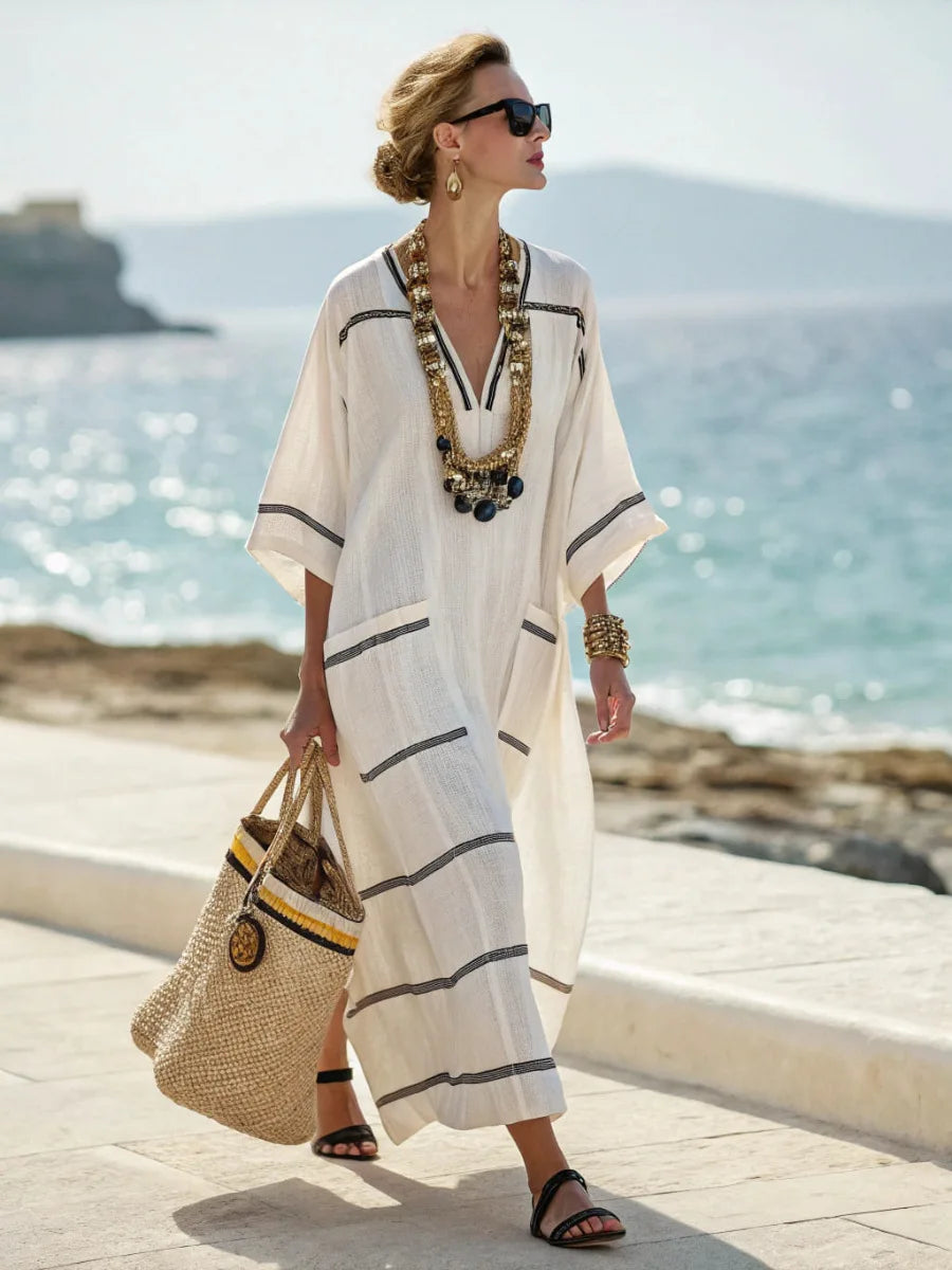 Woman in a white and black striped dress standing by the ocean