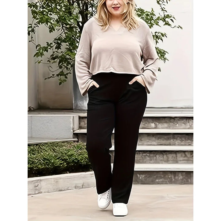 Front View Of Women's Plus Size Black Pants With Hands In Pockets And White Sneakers