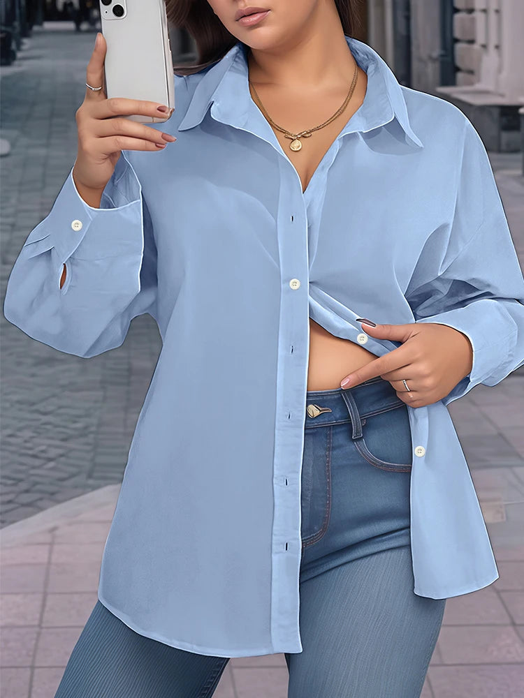 Person wearing a light blue shirt and jeans, taking a mirror selfie.