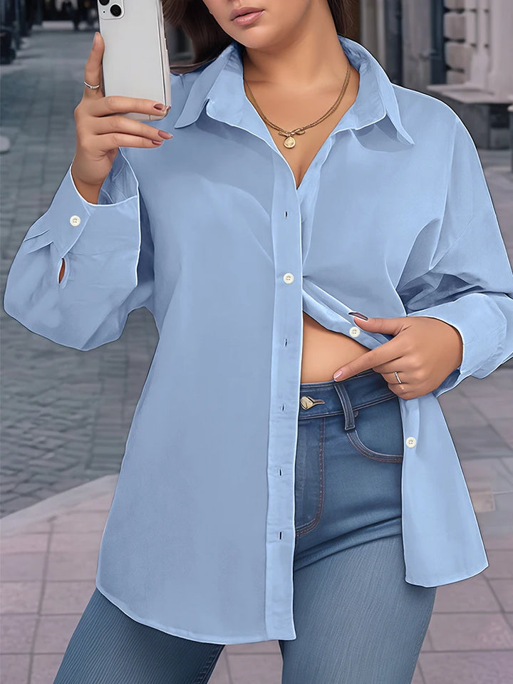 Person wearing a light blue shirt and jeans, taking a mirror selfie.