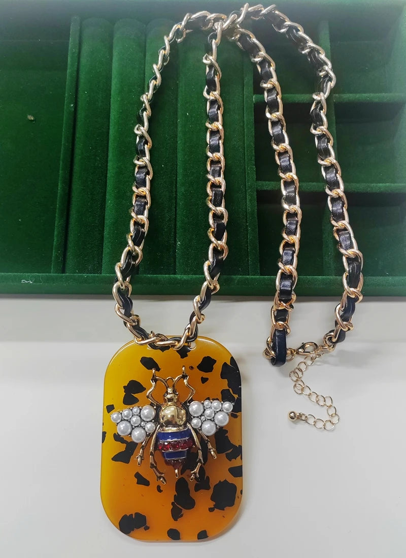 Necklace with a decorative pendant featuring a beetle design on a green and white background