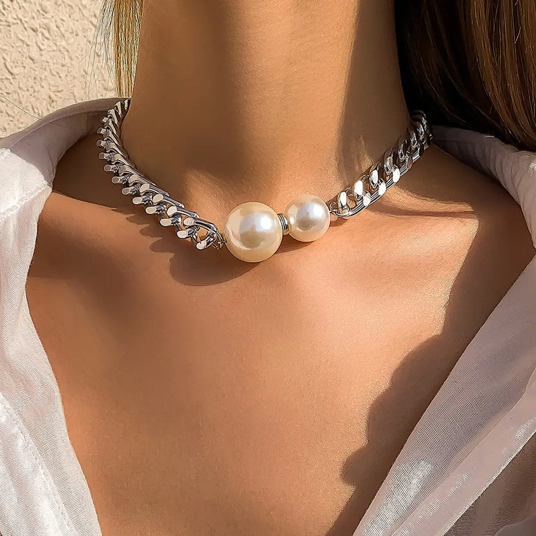Pearl necklace with silver chain on a person wearing a white blouse.