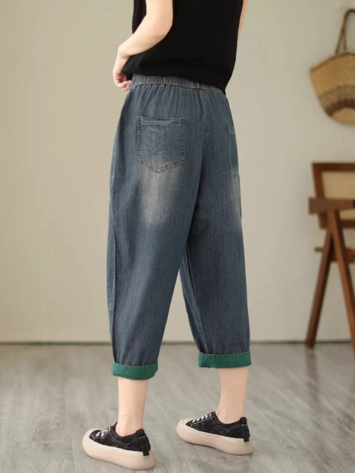 Person wearing blue denim pants with green cuffs in a room setting.