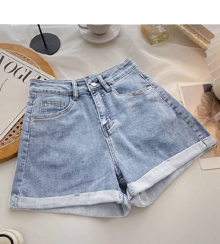 Light blue denim shorts on a surface with a magazine and other items in the background
