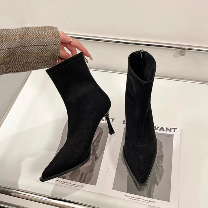 Black suede ankle boots with pointed toe and slim high heel, close-up