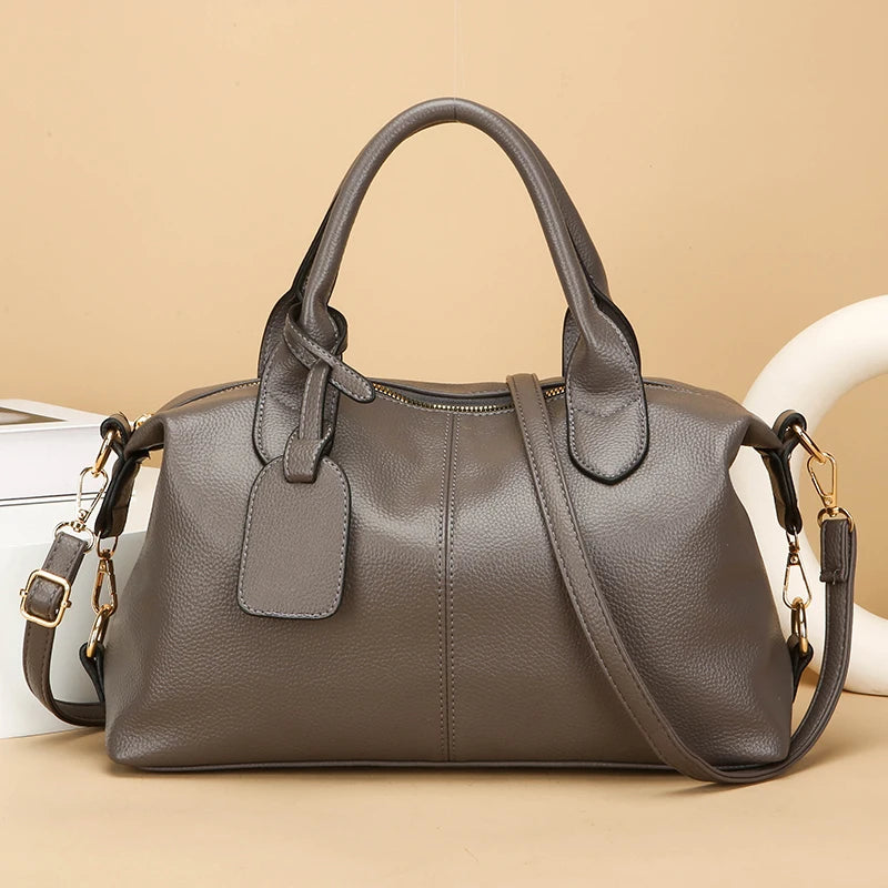 Women's soft leather tote bag in gray with top handles and crossbody strap