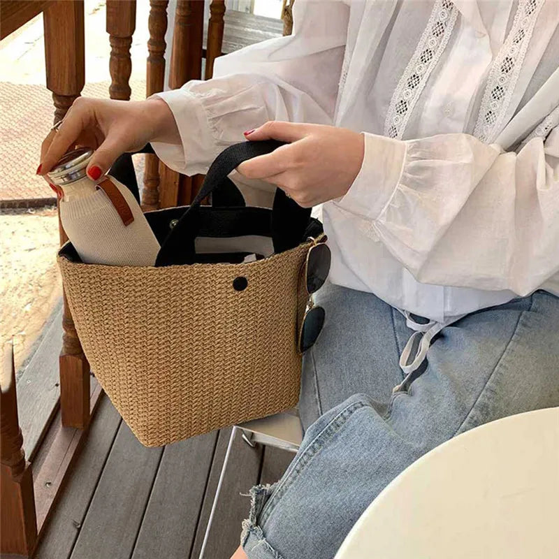 Beige woven straw bucket handbag with black handles and round side button details