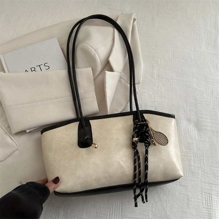 Cream PU leather tote handbag with black handles and braided crossbody tassel charm