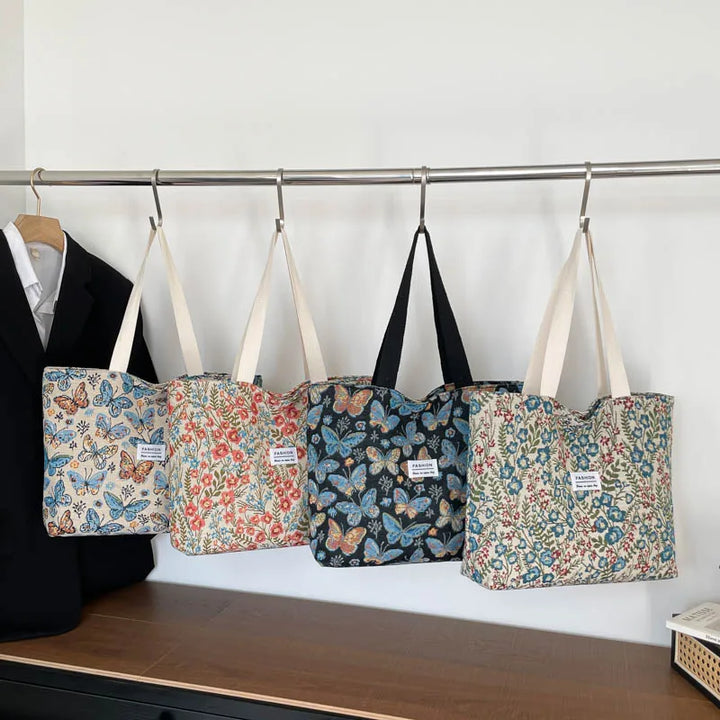 Canvas tote bag set on display with multiple floral butterfly prints and handles