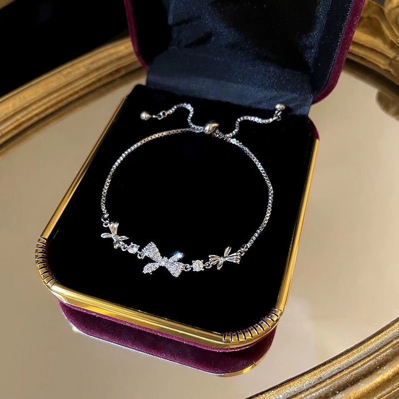 Silver-tone crystal tennis bracelet with bow-shaped charms and pavé stones