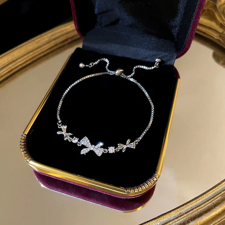 Silver-tone crystal tennis bracelet with bow-shaped charms and pavé stones