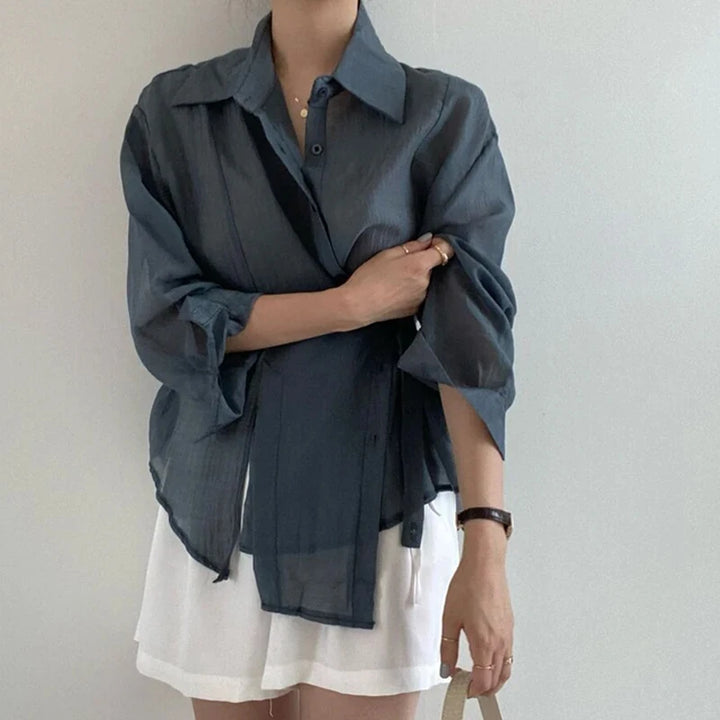 Person wearing a dark blue oversized shirt over a white dress against a plain background