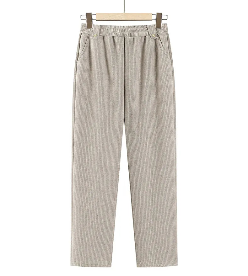 A pair of light beige ribbed knit pants with an elastic waistband and decorative buttons, hanging from a wooden hanger against a plain white background.