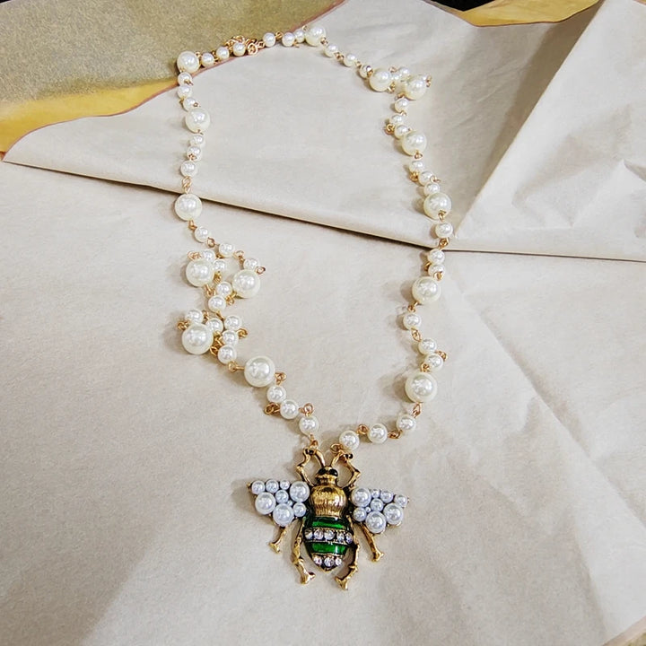 Pearl necklace with a bee pendant on a light fabric background