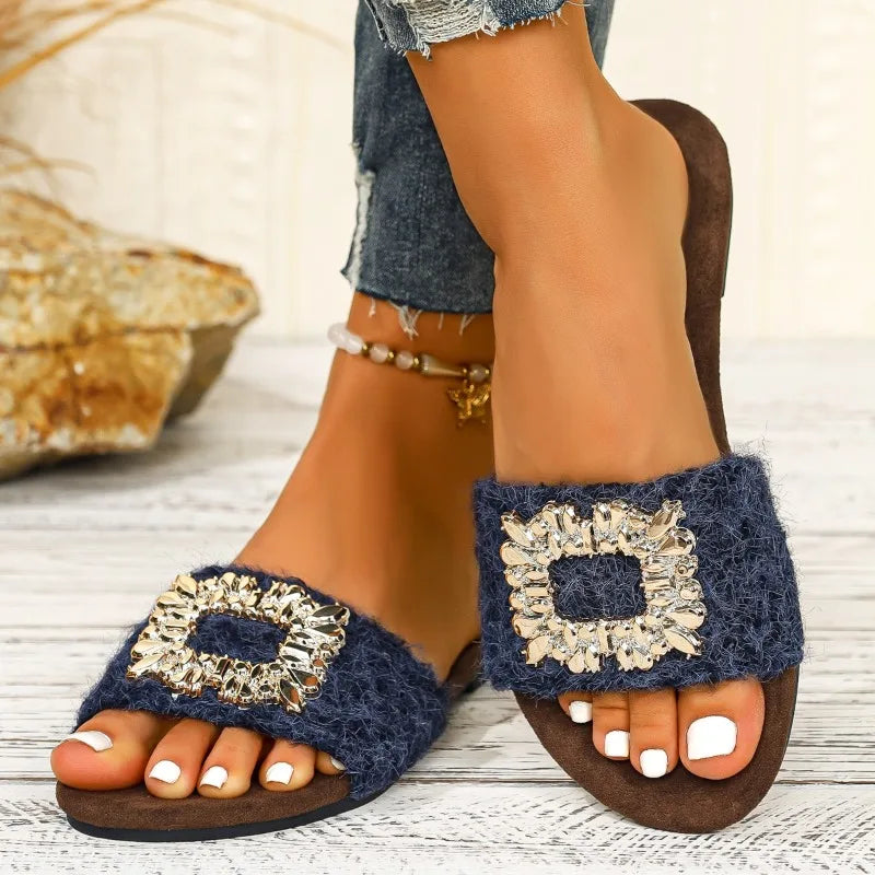 Navy blue sandals with decorative embellishments on a light wooden floor.