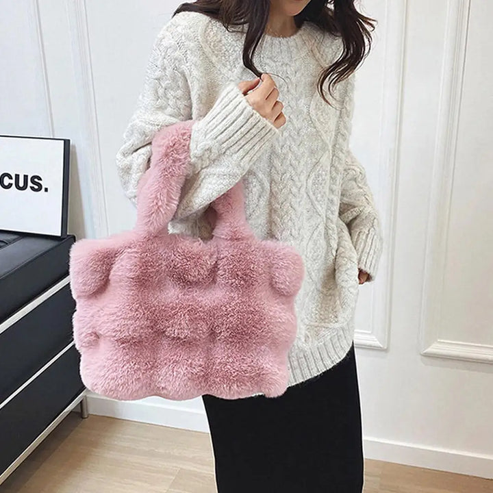 Pink faux fur bucket handbag with short handles and plush textured surface