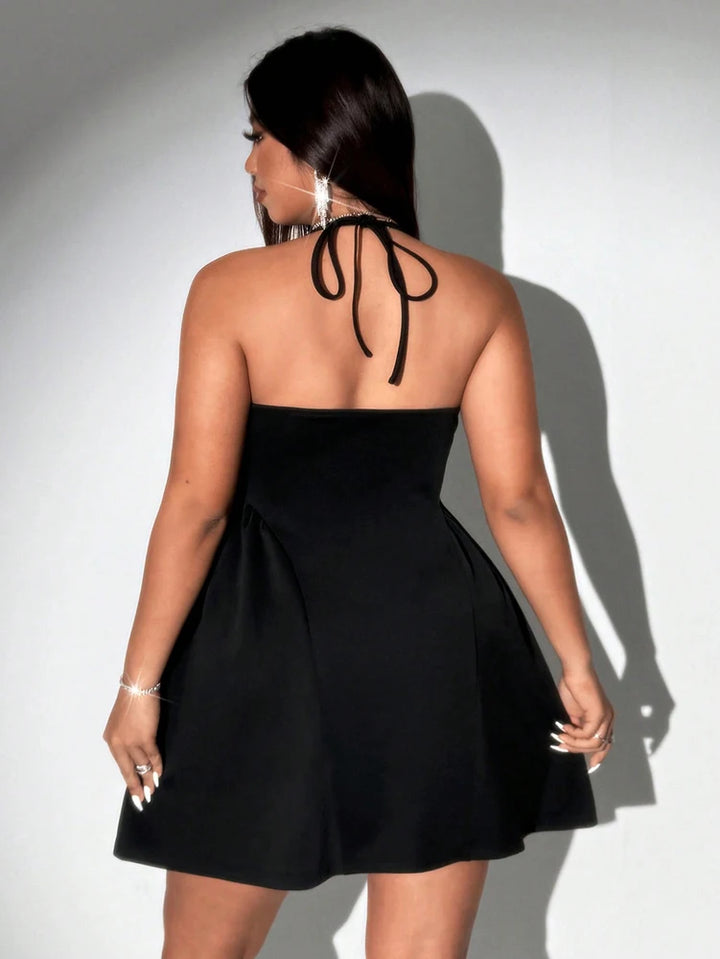 Woman wearing a black halter neck dress against a white background