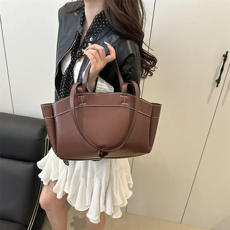 Woman holding a brown handbag in an indoor setting