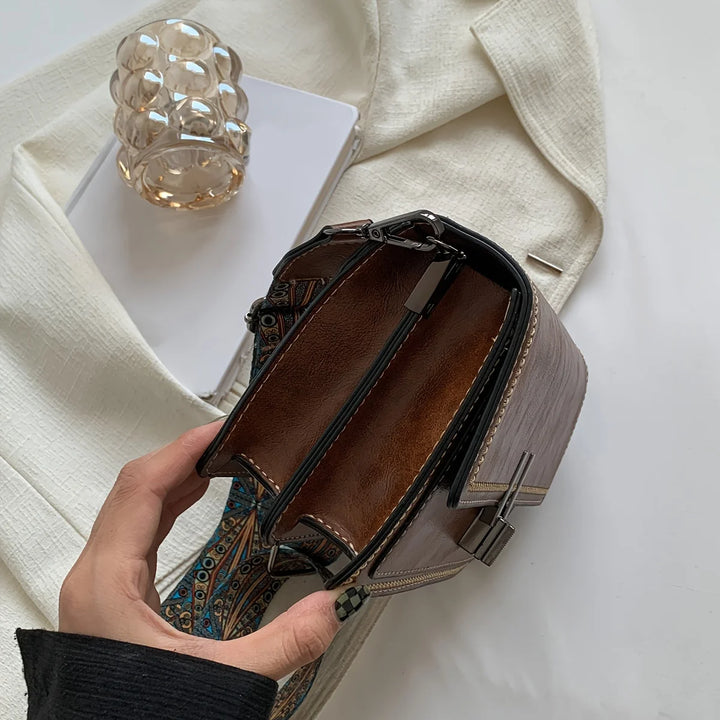Mini crossbody bag in brown with open interior and patterned strap, side view