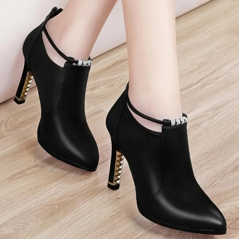 Black high-heeled ankle boots with studded details on a wooden floor.