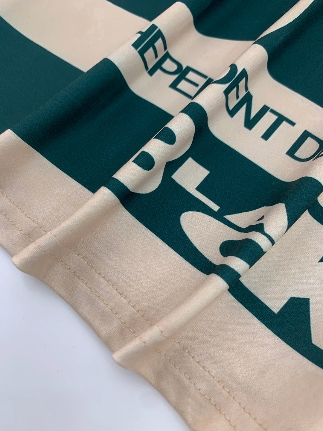 T-shirt hem and stitched cuff close-up with dark green graphic letters on cream