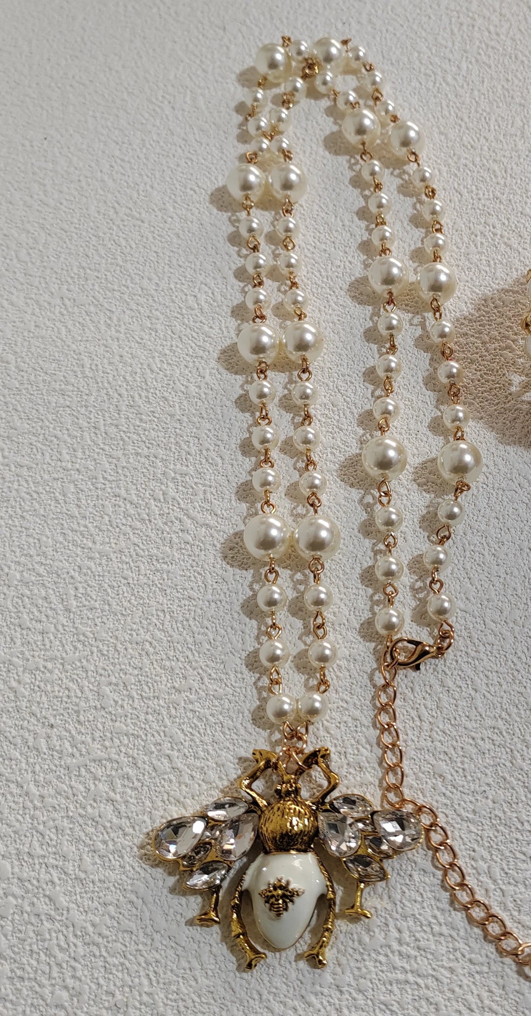 Pearl necklace with a decorative pendant on a light gray background