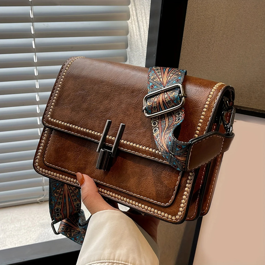 Mini crossbody bag in brown with flap lock and beaded trim, featuring a patterned strap