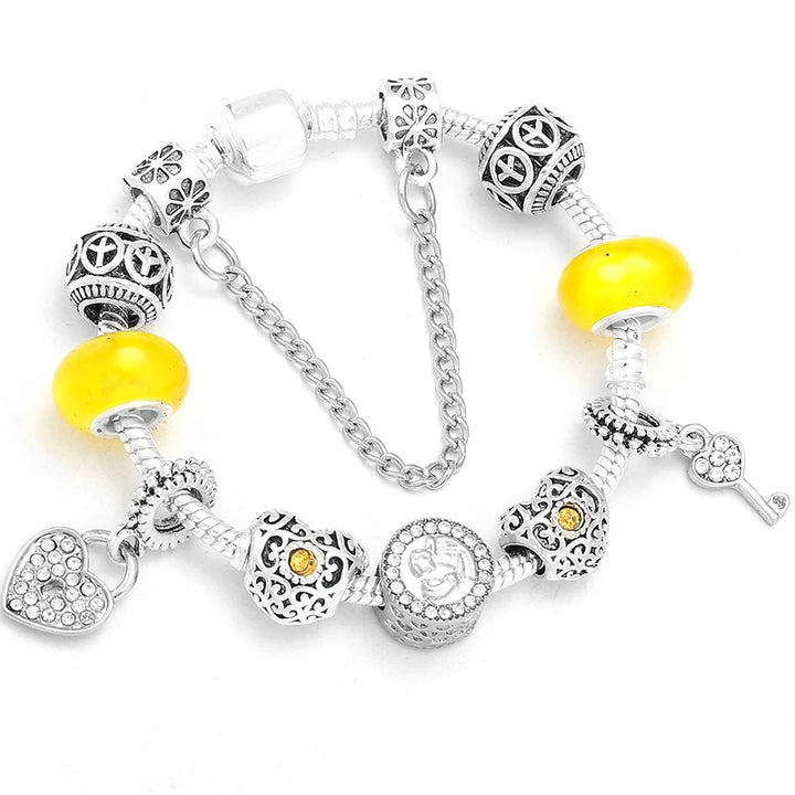 Silver bracelet with yellow bead charms, heart links, and key pendant detail