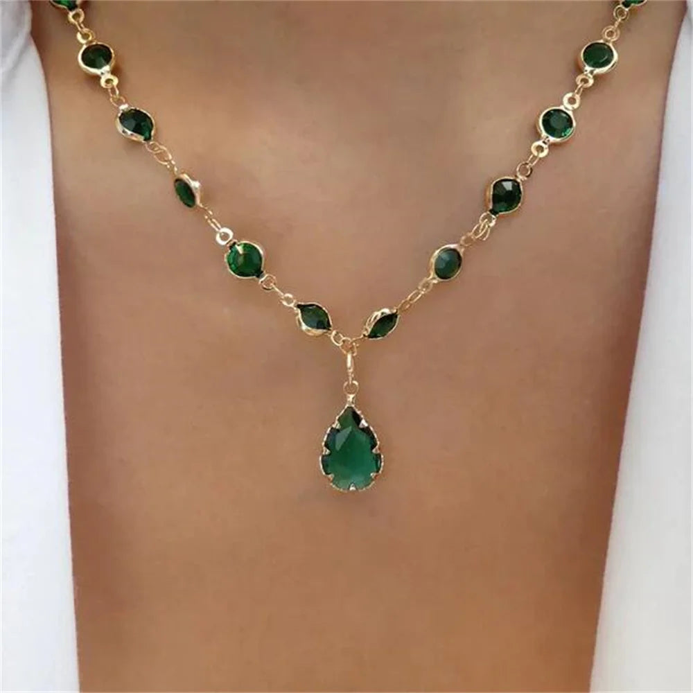 Gold-tone beaded necklace with green oval stones and a central green teardrop pendant.
