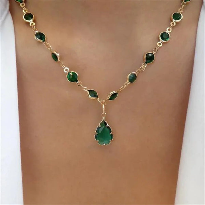 Gold-tone beaded necklace with green oval stones and a central green teardrop pendant.