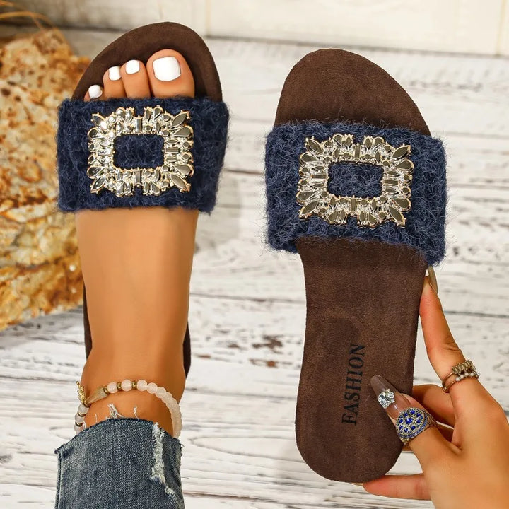 Brown sandals with blue embellishments on a wooden surface