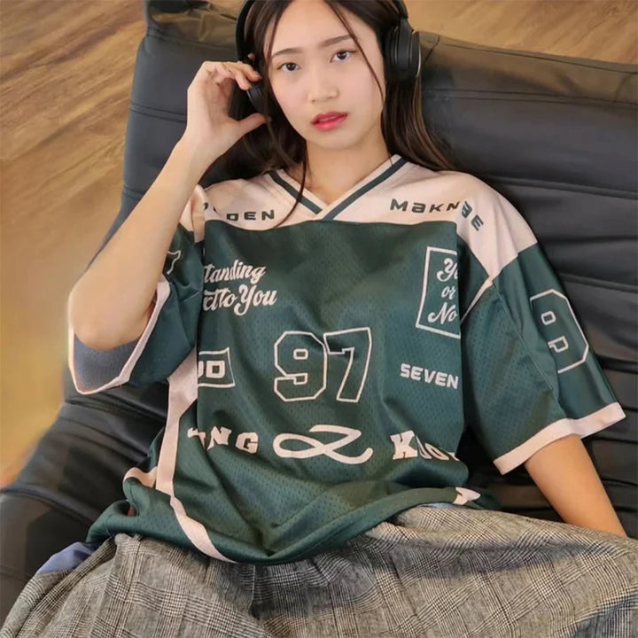 Person wearing a green and beige sports jersey with text, sitting on a couch.