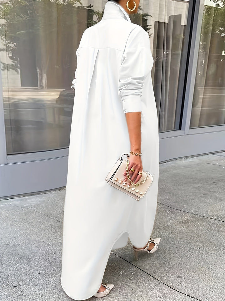 Person wearing a long white dress holding a small handbag on a sidewalk.