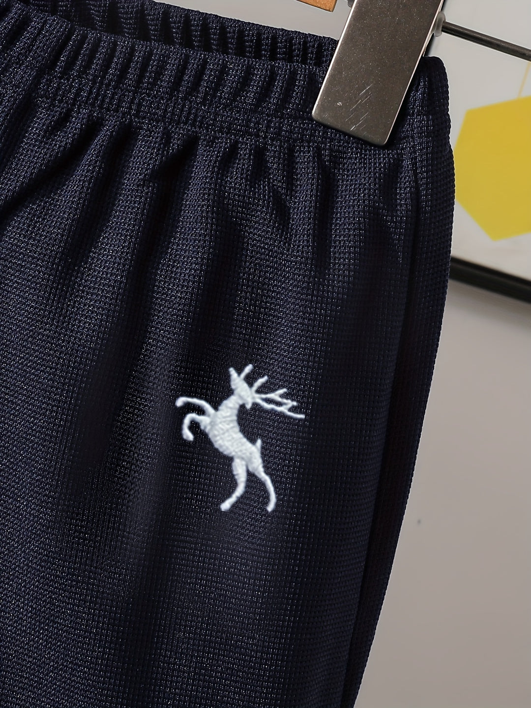 Navy blue fabric with a white embroidered deer design on a neutral background
