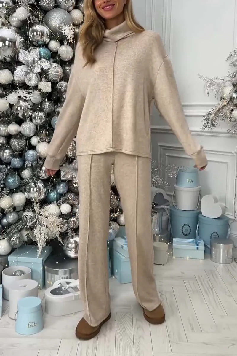 Woman in beige outfit standing in a room with decorative Christmas tree and presents.