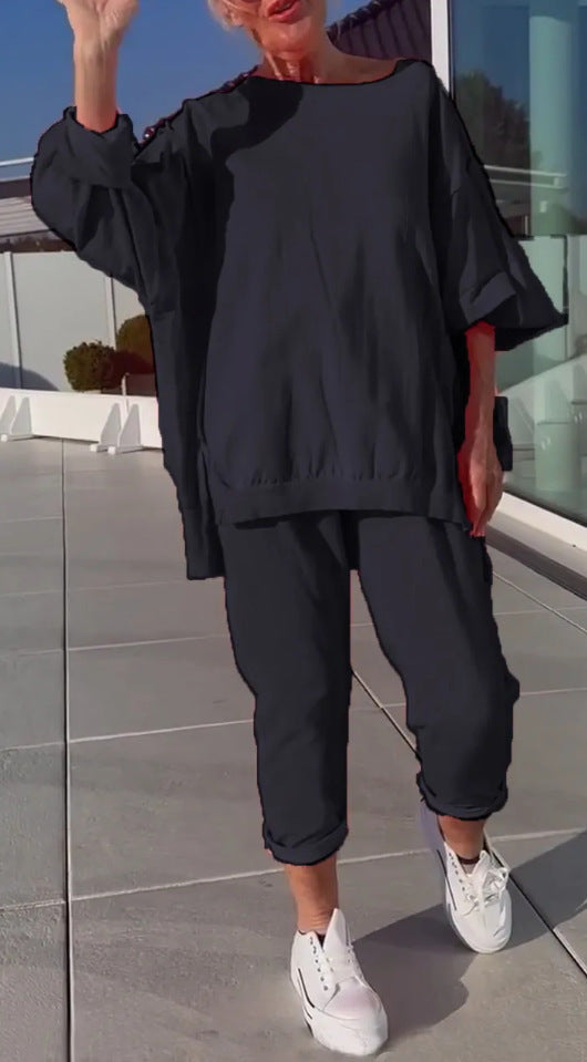 Person wearing a black outfit with white sneakers on a tiled floor.