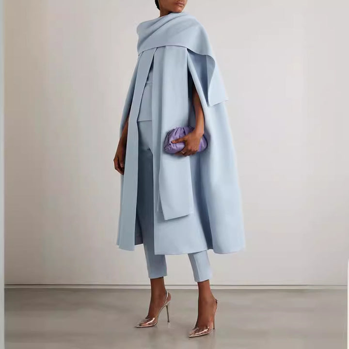 Person wearing a light blue outfit with a matching shawl against a plain background