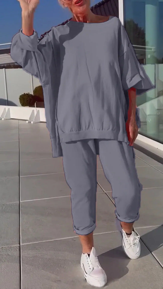 Person wearing a gray outfit with white sneakers on a reflective surface.